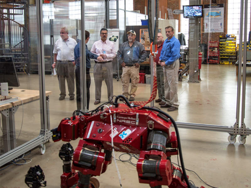 A group observes the robot, CHIMP at the National Robotics Engineering Center (NREC). 